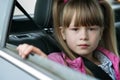 Little child girl sitting in a car on rear seat fastened with safety belt Royalty Free Stock Photo