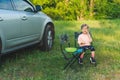 Little child girl sitting on chair near car outdoor Royalty Free Stock Photo