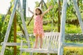 Little child girl is swinging on a swing in summer park. Sunny joyful summer day. Child swinging on playground on sunny Royalty Free Stock Photo