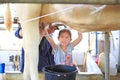 Little child girl training milking a cow by hands in dairy production farm