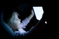 Little child girl using tablet technology in bed by night at home. Happy surprised kid daughter in bedroom watching Royalty Free Stock Photo