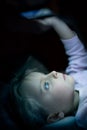 Little child girl using tablet technology in bed by night at home. Serious or toughtful kid daughter in bedroom watching