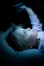 Little child girl using tablet technology in bed by night at home. Serious or toughtful kid daughter in bedroom watching