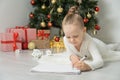 Little child girl writes letter to Santa Claus and dreams of a gift background Christmas tree. Royalty Free Stock Photo