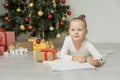 Little child girl writes letter to Santa Claus and dreams of a gift background Christmas tree. Royalty Free Stock Photo