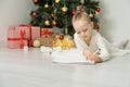 Little child girl writes letter to Santa Claus and dreams of a gift background Christmas tree. Royalty Free Stock Photo