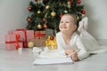 Little child girl writes letter to Santa Claus and dreams of a gift background Christmas tree. Royalty Free Stock Photo