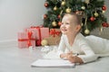 Little child girl writes letter to Santa Claus and dreams of a gift background Christmas tree. Royalty Free Stock Photo