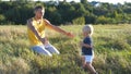 Little child goes on green grass at the field to his father at sunny day. Dad lifting up his baby boy at nature. Happy Royalty Free Stock Photo