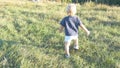 Little child goes on green grass at the field to his father at sunny day. Happy family on a summer meadow. Baby boy Royalty Free Stock Photo