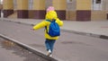 a little child goes to school with blue backpack, funny school weekdays kid, girl student walks around the schoolyard of