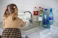 Little child helps sort plastic for recycling in the kitchen. A child helps his mother put plastic bottles into boxes to