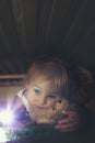 Little child, hiding under the bed, hugging teddy bear and holding flashlight Royalty Free Stock Photo