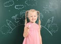 Little child holding chalk near blackboard with drawing Royalty Free Stock Photo