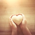 Little child holding a wooden heart. father`s and mother`s day, love, hope and religion concept Royalty Free Stock Photo