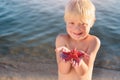 Little child holds starfish on his palm. Blond boy smiles and shows large starfish Royalty Free Stock Photo