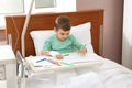 Little child with intravenous drip drawing in bed Royalty Free Stock Photo