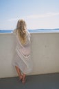 Adorable girl with long blond hair looking from the balcony back view