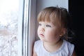 Little child looking out window. baby girl wanting to walk outdoors at rainy weather Royalty Free Stock Photo