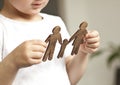 The little child looking on the wooden figures of mom, dad and child in his hands.