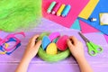Little child makes Easter decoration. Child puts felt Easter egg in a basket