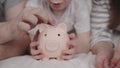 little child with mother and father throw coins of money at pig, happy family saving savings in piggy bank, childhood Royalty Free Stock Photo