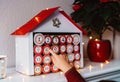 Little child opening handmade advent calendar made from toilet paper rolls.