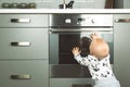 Little child playing with electric stove in the kitchen. Baby safety in kitchen Royalty Free Stock Photo