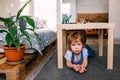 Little child playing hide and seek at home under the children& x27;s table. Royalty Free Stock Photo