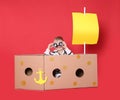 Little child playing with ship made of cardboard box on background Royalty Free Stock Photo