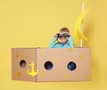 Little child playing with ship made of cardboard box on background Royalty Free Stock Photo