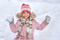 A little child is playing snowballs. The notion of winter rest and children entertainment. A girl with snow in her hands