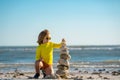 Little child playing with stones on the beach. Child play with pyramid of stones on the beach, sea seascape, rest and Royalty Free Stock Photo