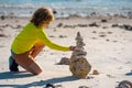 Little child playing with stones on the beach. Child play with pyramid of stones on the beach, sea seascape, rest and Royalty Free Stock Photo