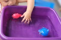 Little child plays with plastic toys in a basin of water, concept of summer games, fun, child development, happy childhood, Royalty Free Stock Photo