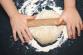 Little child preparing dough for backing. Kid`s hands, some flour, wheat dough and rolling-pin on the black table. Children hands Royalty Free Stock Photo