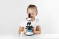 Little child prodigy girl looks through a microscope  studying in the laboratory. Interesting experiments for children Royalty Free Stock Photo