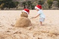 Little child in red santa hat with sand snowman on beach Royalty Free Stock Photo