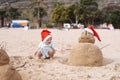 Little child in red santa hat with sand snowman on beach Royalty Free Stock Photo