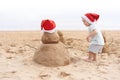 Little child in red santa hat with sand snowman on beach Royalty Free Stock Photo