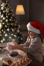 Little child in Santa hat making Christmas cookies at  home Royalty Free Stock Photo