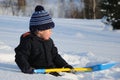 Little child with shovel sitting on snow Royalty Free Stock Photo