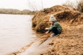 Little child sit on the shore of the lake and playing with water. Happy kid boy playing and having fun outdoors over Royalty Free Stock Photo