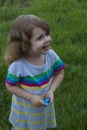 Little child smiles and plays with spinner on background of green grass