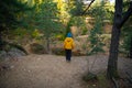 A little child is standing on the edge of a cliff, there is a small lake below