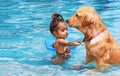 Little child swim with dog in blue swimming pool Royalty Free Stock Photo