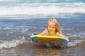 Little child swimming with bodyboard on the sea waves