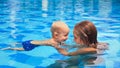 Little child swimming in pool with mother