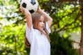 Little child throwing a ball from over her head. Girl playing with a football in a park, portrait. Young sporty kid Royalty Free Stock Photo