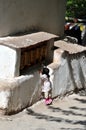 Little child on tiptoe to reach praying wheels